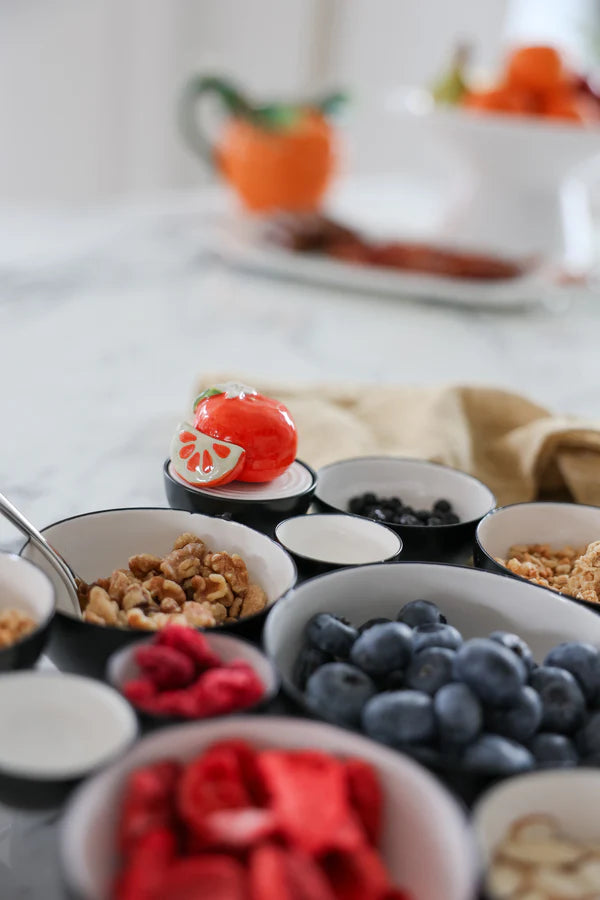 Assorted fruits and nuts in small bowls on a table.
