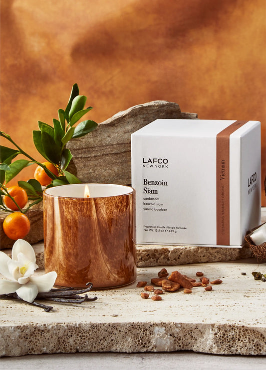 LAFCO candle and packaging on a rustic surface with fruits and flowers