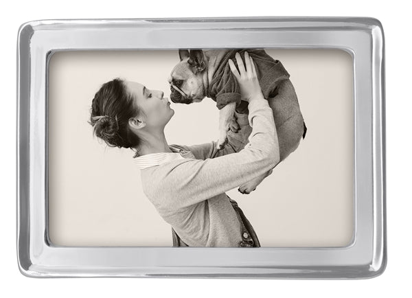 A silver edged 4" by 6" frame with a stock picture of woman kissing her dog.