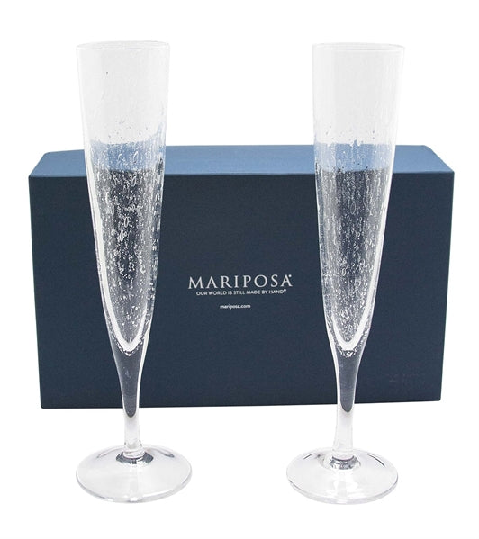 Two champagne flutes in front of a navy blue Mariposa gift box.