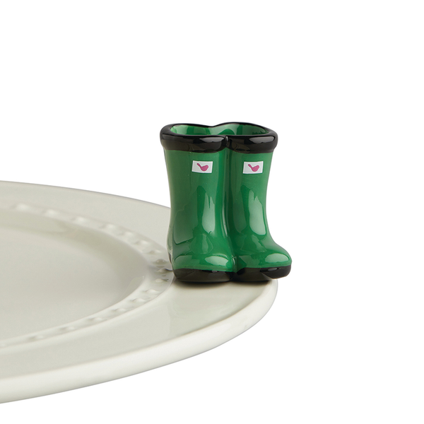 Porcelain hunter green galoshes with a pink Nora Fleming logo on the top front.