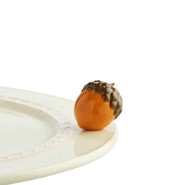 An acorn ornament attached to a Nora Fleming serving piece. 