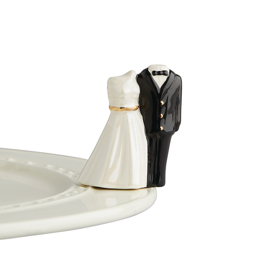 A porcelain silhouette of a bridal gown and tuxedo.