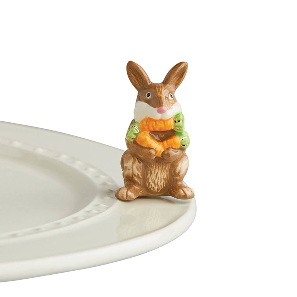 A porcelain bunny holding three carrots.