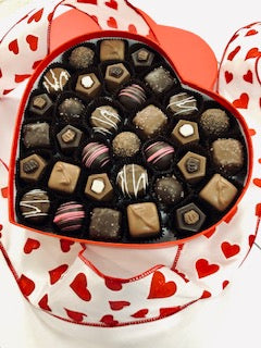 A large red heart shaped box filled with assorted chocolates.