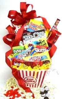 A red striped popcorn bucket overflowing with theater candy and popcorn with a big red ribbon.