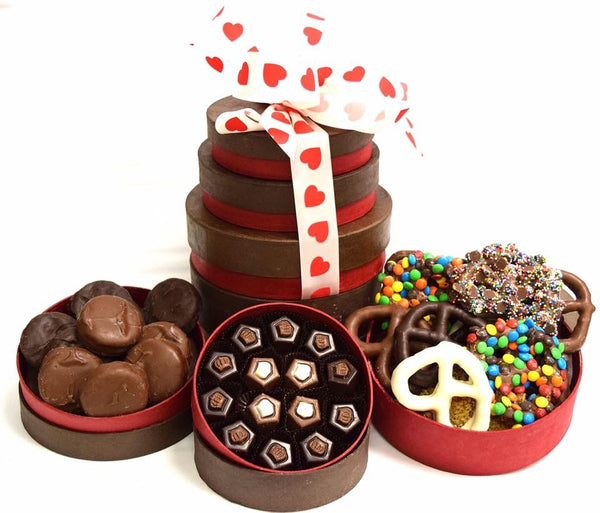 A gift tower overflowing with chocolates and stacked high with a heart printed ribbon. 